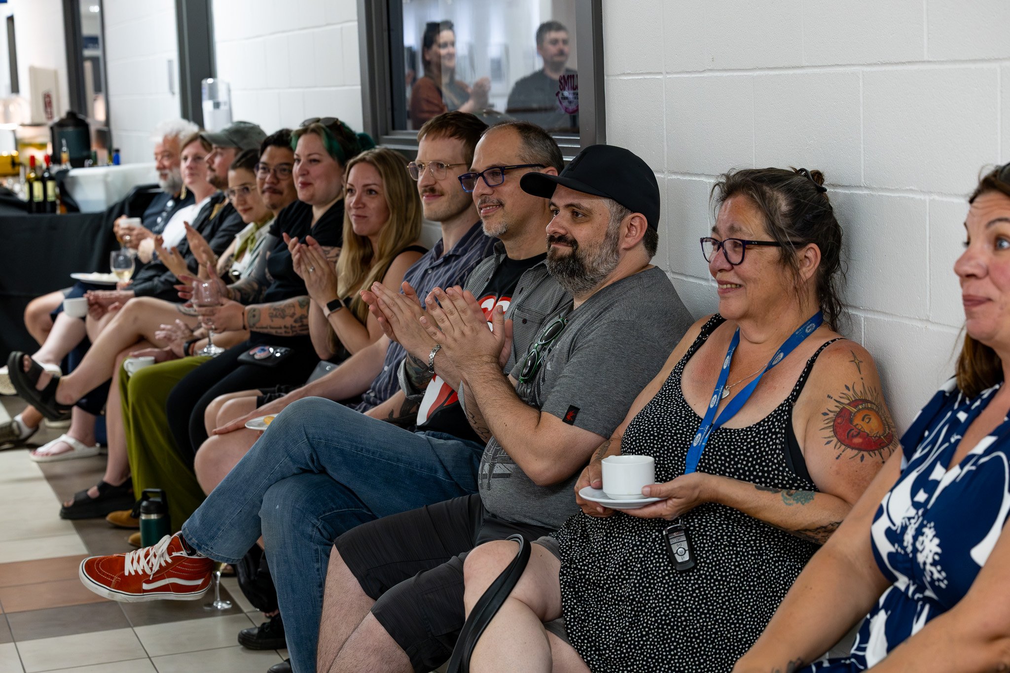 Mixed crowd of adults seated on chairs claps