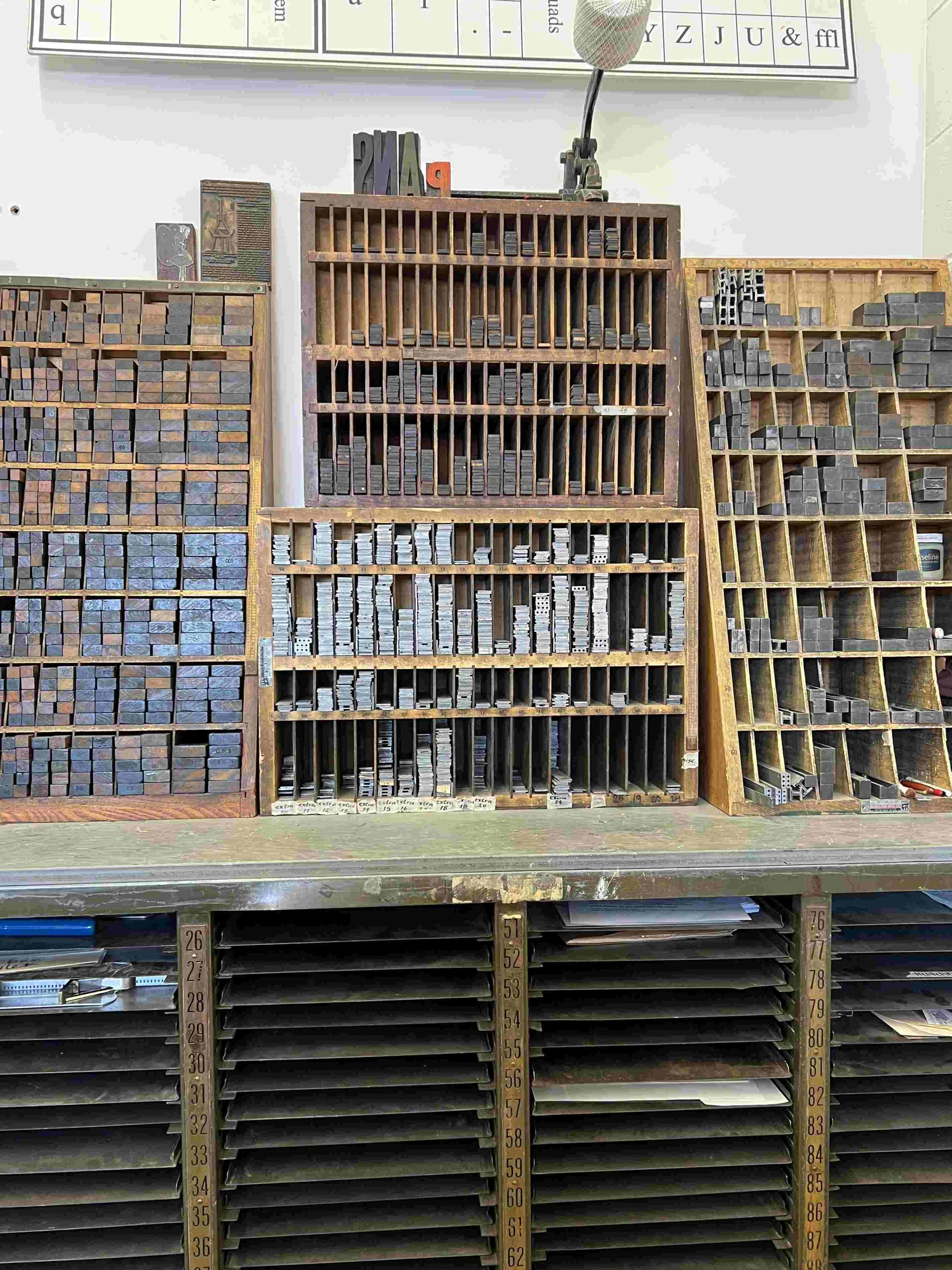 stacks of shelving units with letterpress furniture sit above letterpress assembly storage shelves