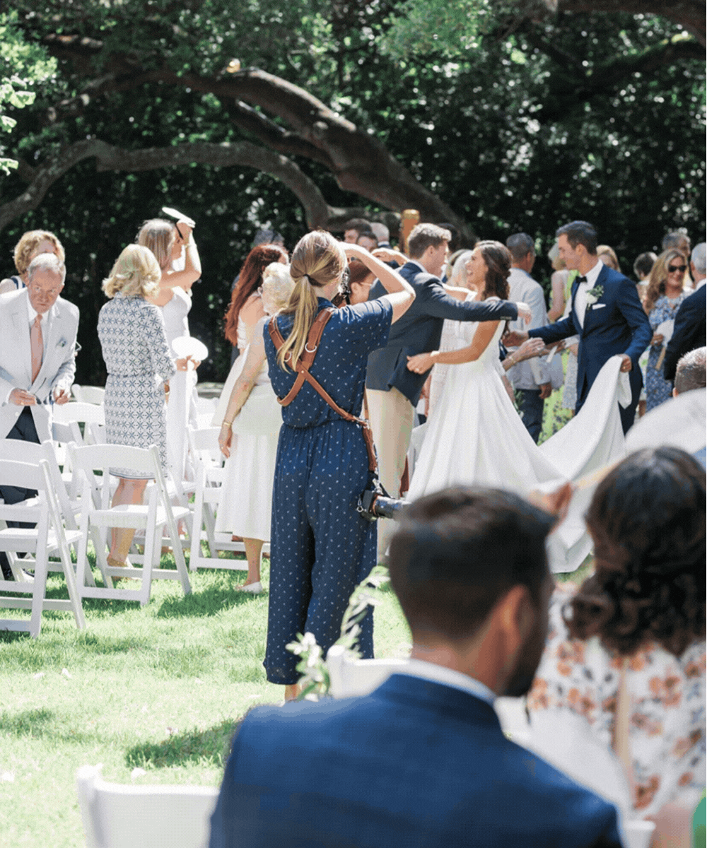 A wedding ceremony outdoors with guests and a couple dancing under a large tree.