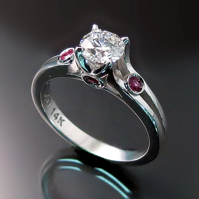This engagement ring was commissioned by a client wishing to incorporate rubies from a ring inherited from a grandparent. Old and new came together beautifully in this contemporary custom made engagement ring.