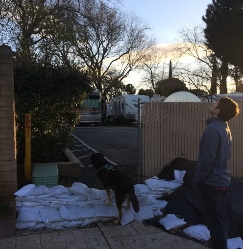 Paul and Odin cross the sandbag wall back into the RV park. The RV park is actually on the river side of the barrier--the sandbags protect the neighborhood, just not our neighborhood. (Peep the Hornet!)