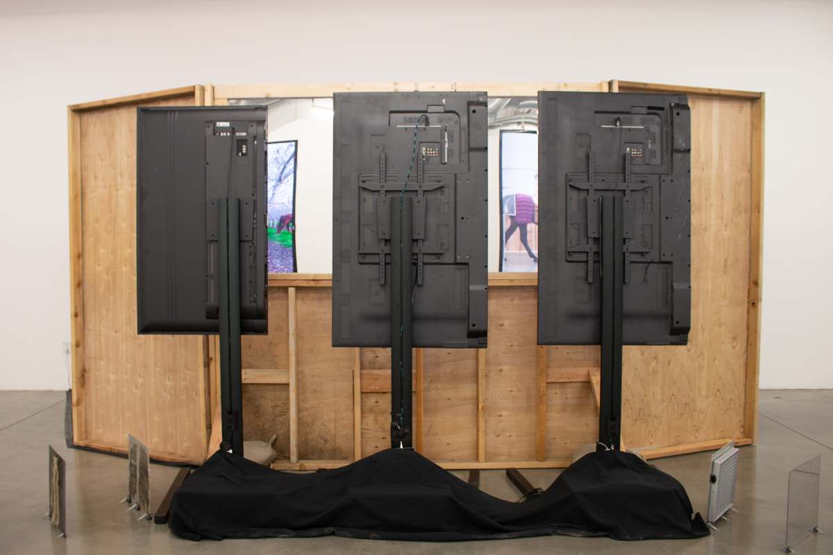 “Untitled Mirage 2, or an Exhibitionary Complex (The Lynda and Stewart Resnick Cultural Center)” Wood Structure, One Way Mirror, Sandbags, Three Channel Video Installation. 2017 work in situ, completed 2018.