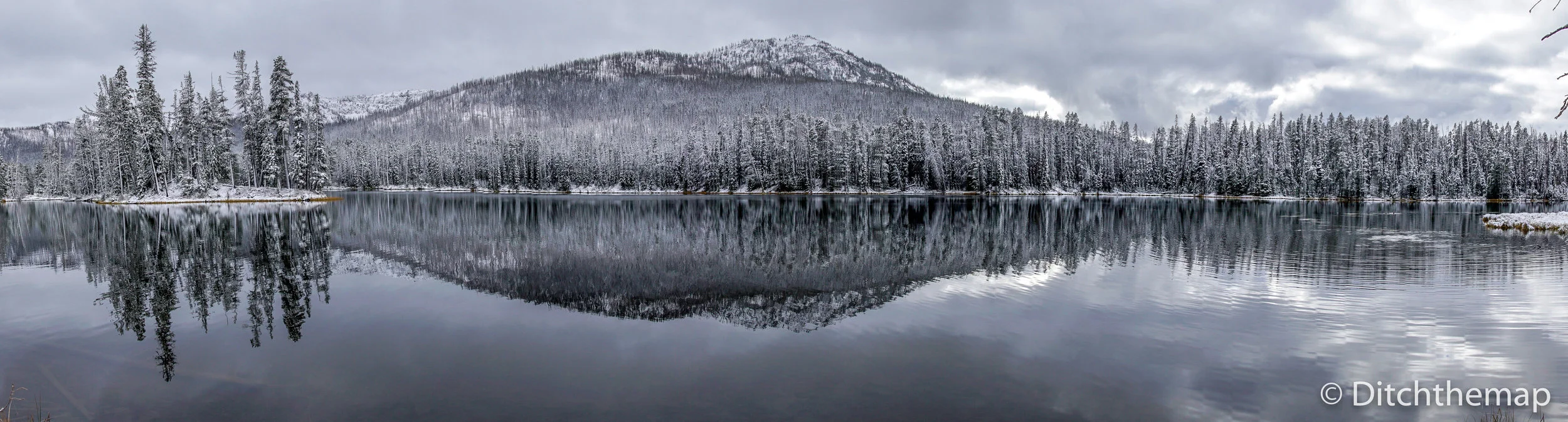 Light snow covered strees and mountain with reflection on lake