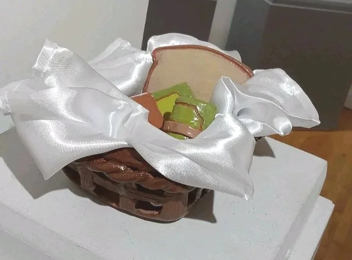 A small decorative basket with bread of various types, lined with white silky cloth.