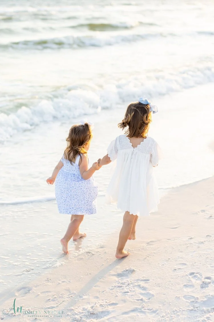 two young girls running along 30a at sunset for their family portraits
