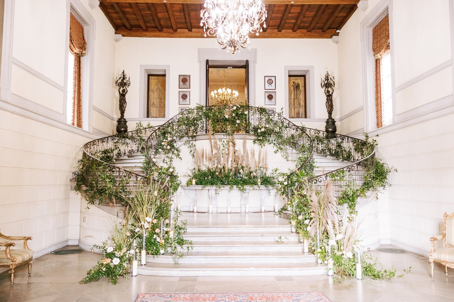 Garlands of greenery and white blooms climbing the grand staircase at Oheka Castle
