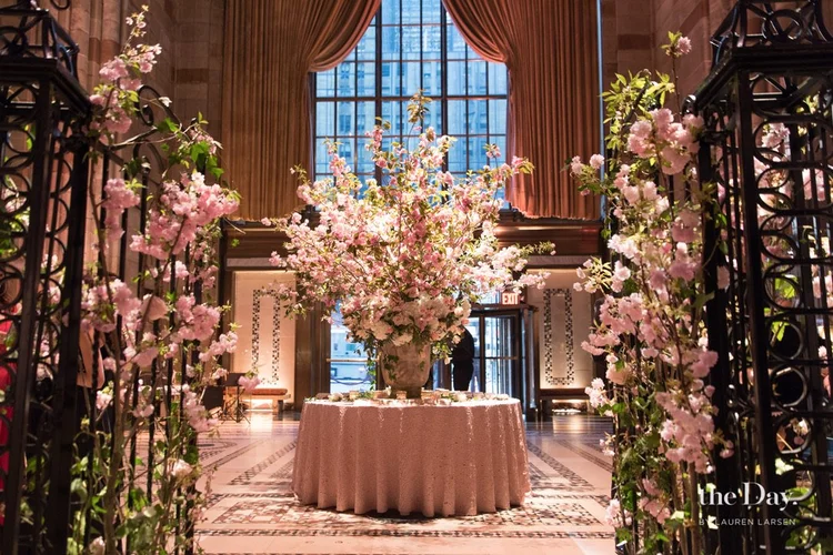 An entrance hall with a towering pink and white arrangement beneath tall windows