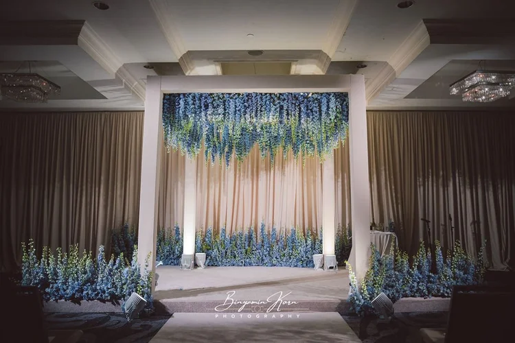 A white chuppah under a canopy of hanging blue and white flowers