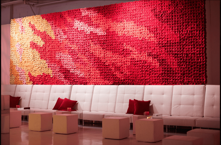 White sofas with red cushions beneath a wall of red and coral flowers