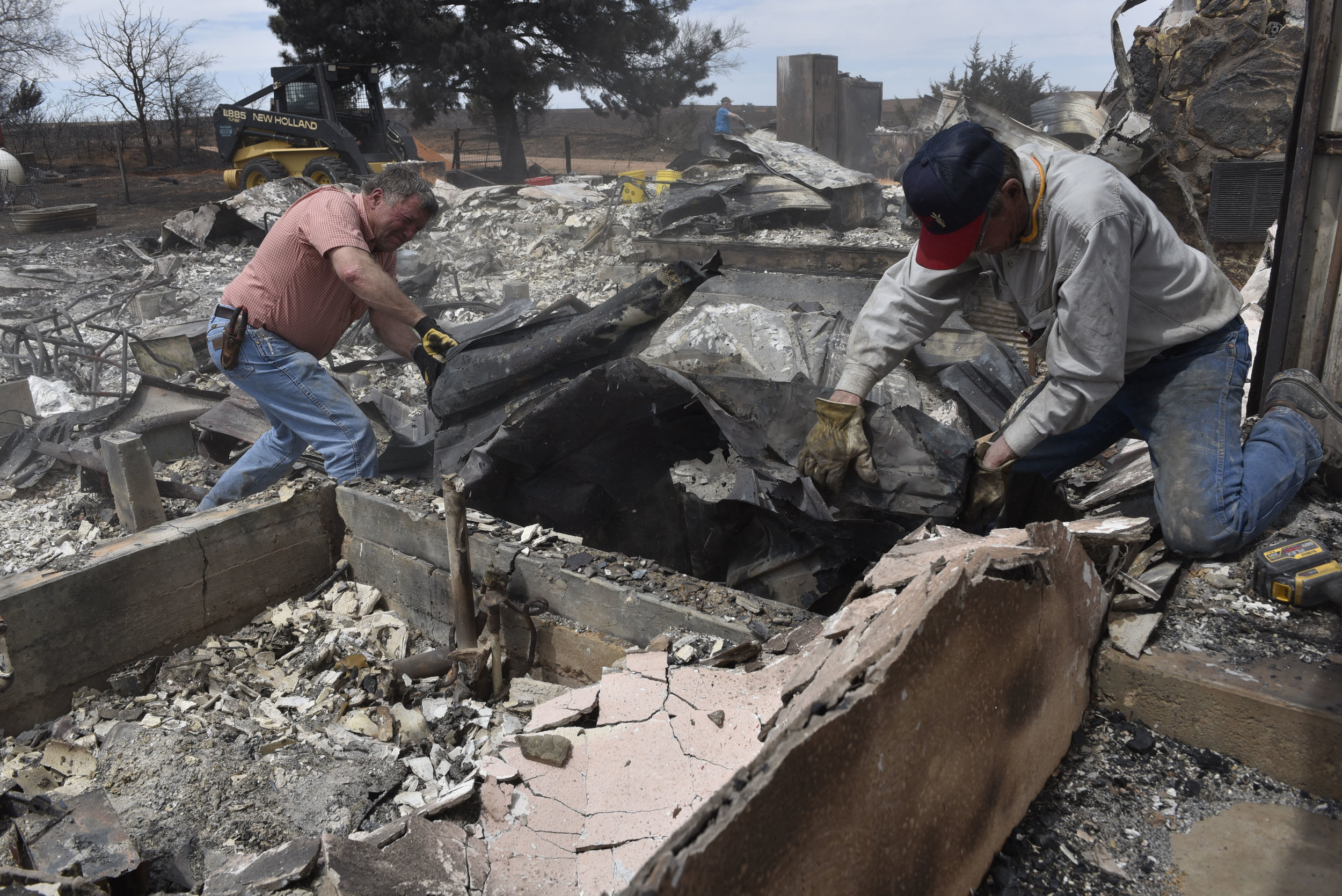  David Bailey, left, and Bobby Yoder remove tin roofing from the remains of Larry and Arlinda Lynes home that was destroyed by the Rhea fire near Taloga, Oklahoma, U.S. April 17, 2018. REUTERS/Nick Oxford 