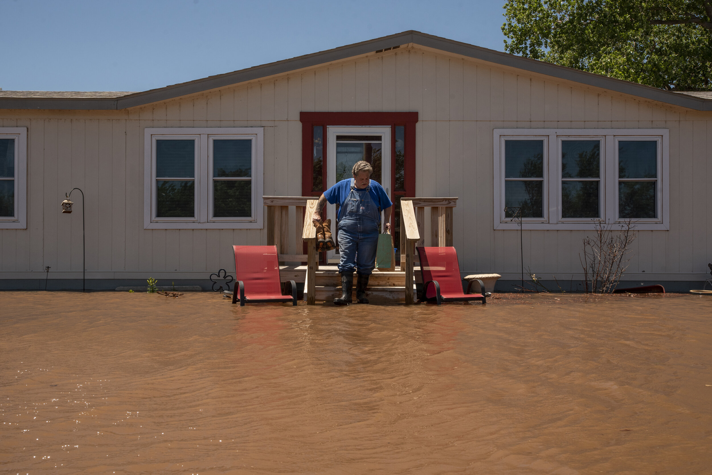  Teri Smith retrieves important belongings as floodwaters rise around his home in Yukon.  Nick Oxford for The New York Times 