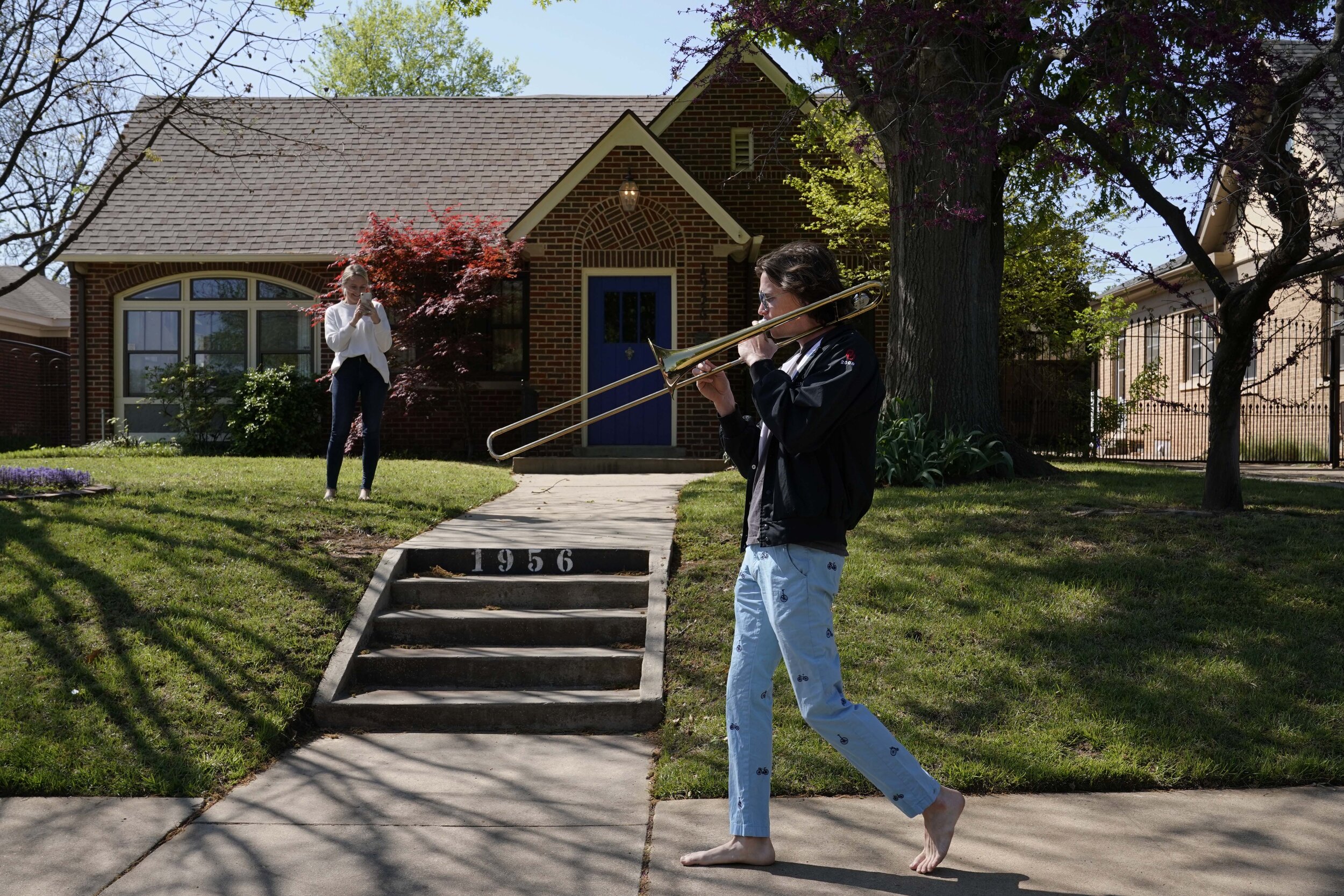  A woman takes a video of Christian Pearson as he plays the trombone during his morning walk amidst an outbreak of the coronavirus disease (COVID-19) in Oklahoma City, Oklahoma, U.S. April 10, 2020. REUTERS/Nick Oxford 