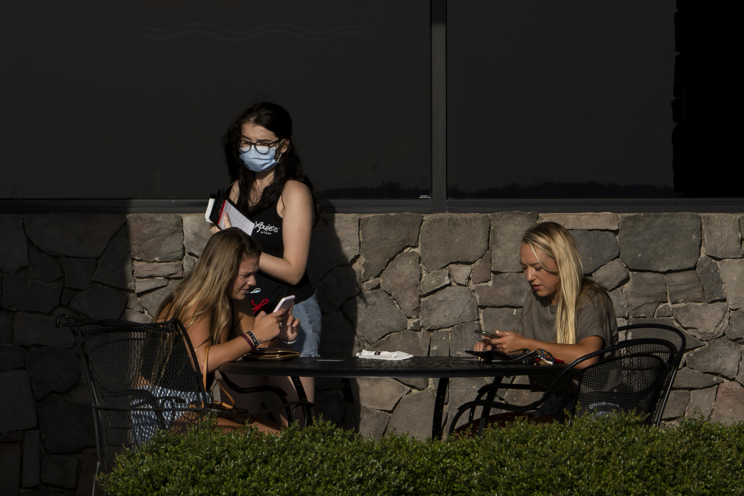  A waitress wearing a protective mask walks past customers on the patio at Louie's Grill and Bar at Lake Hefner in Oklahoma City, Oklahoma on Sunday July 19, 2020. Nick Oxford for The New York Times 