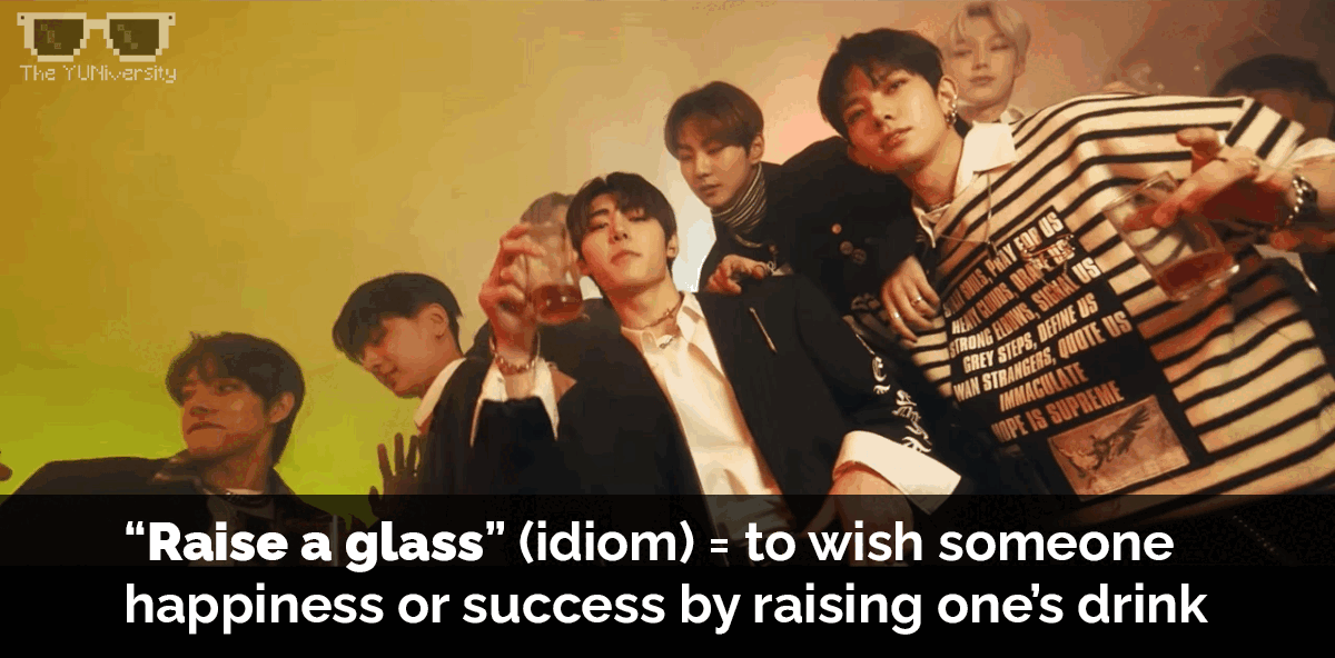 A group of young men in a party or celebration, some holding drinks and making gestures. The background has colorful lighting, and the image includes a black overlay with text explaining the idiom "Raise a glass."