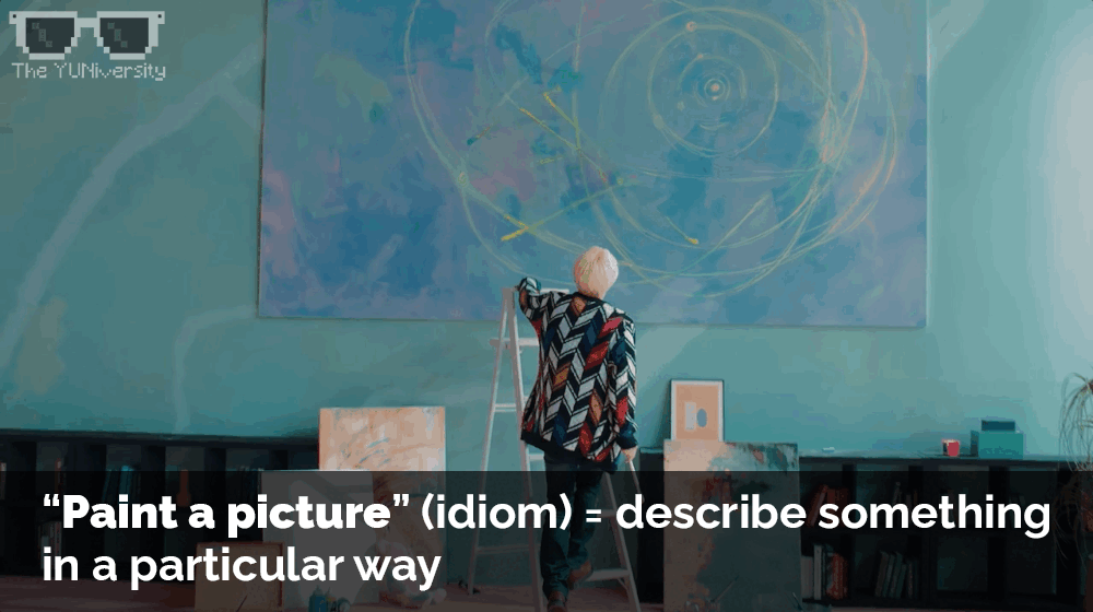 A person with blonde hair standing on a ladder in an art studio, looking at a large abstract painting on the wall. The studio has a teal wall, a cabinet, and some canvases and art supplies. The image includes the text explaining the idiom 'Paint a pi