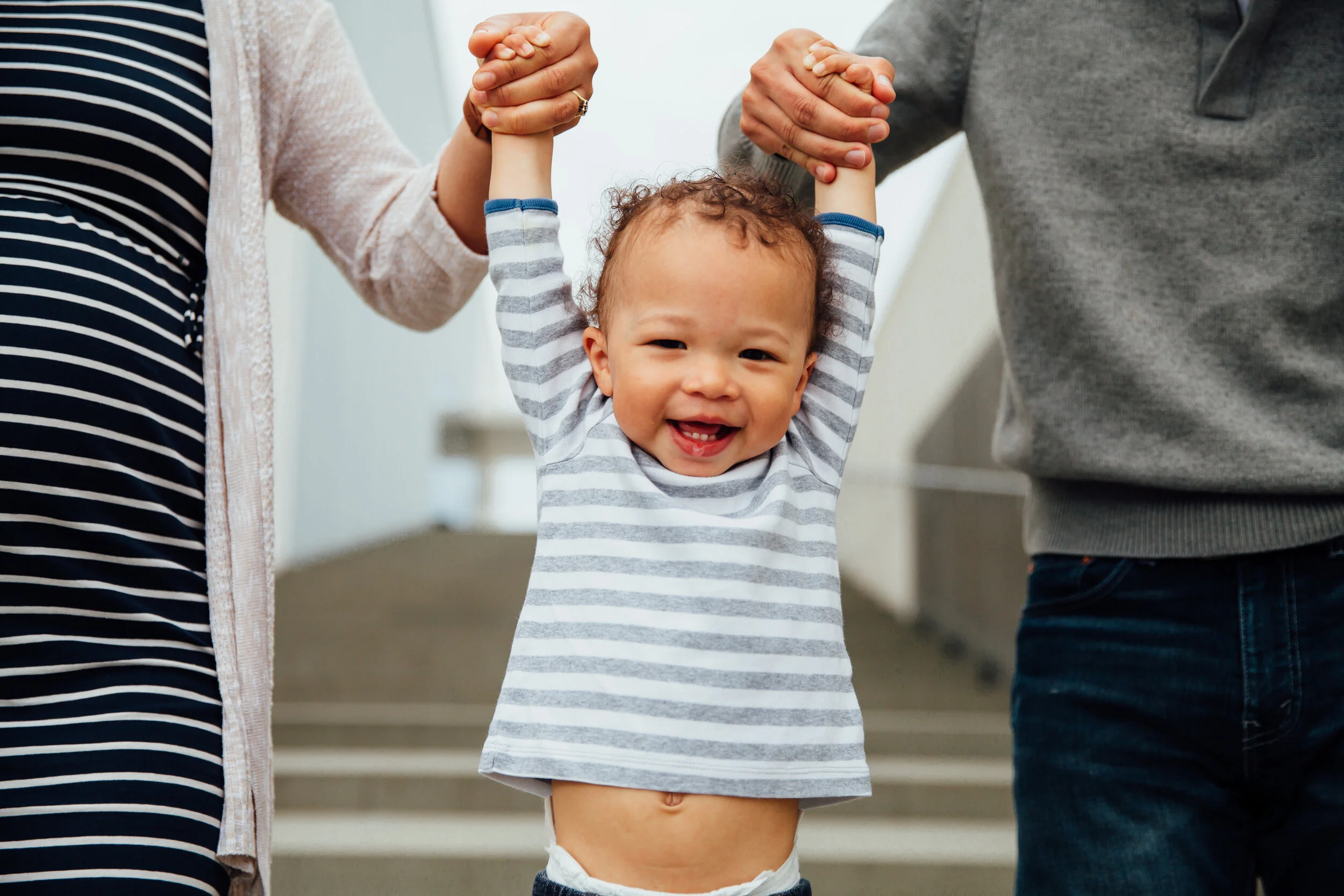 toddler laughing while parents swing him.jpg