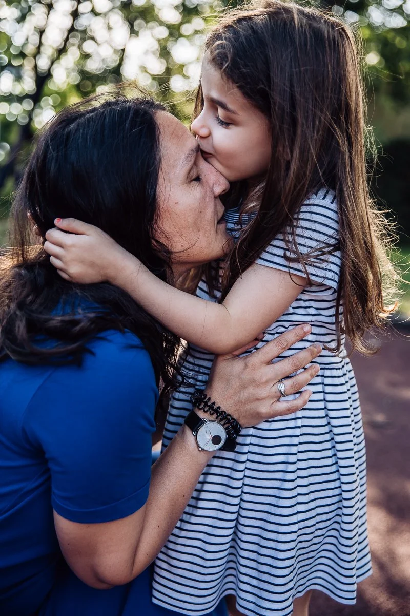 little girl kissing her mom on the forehead