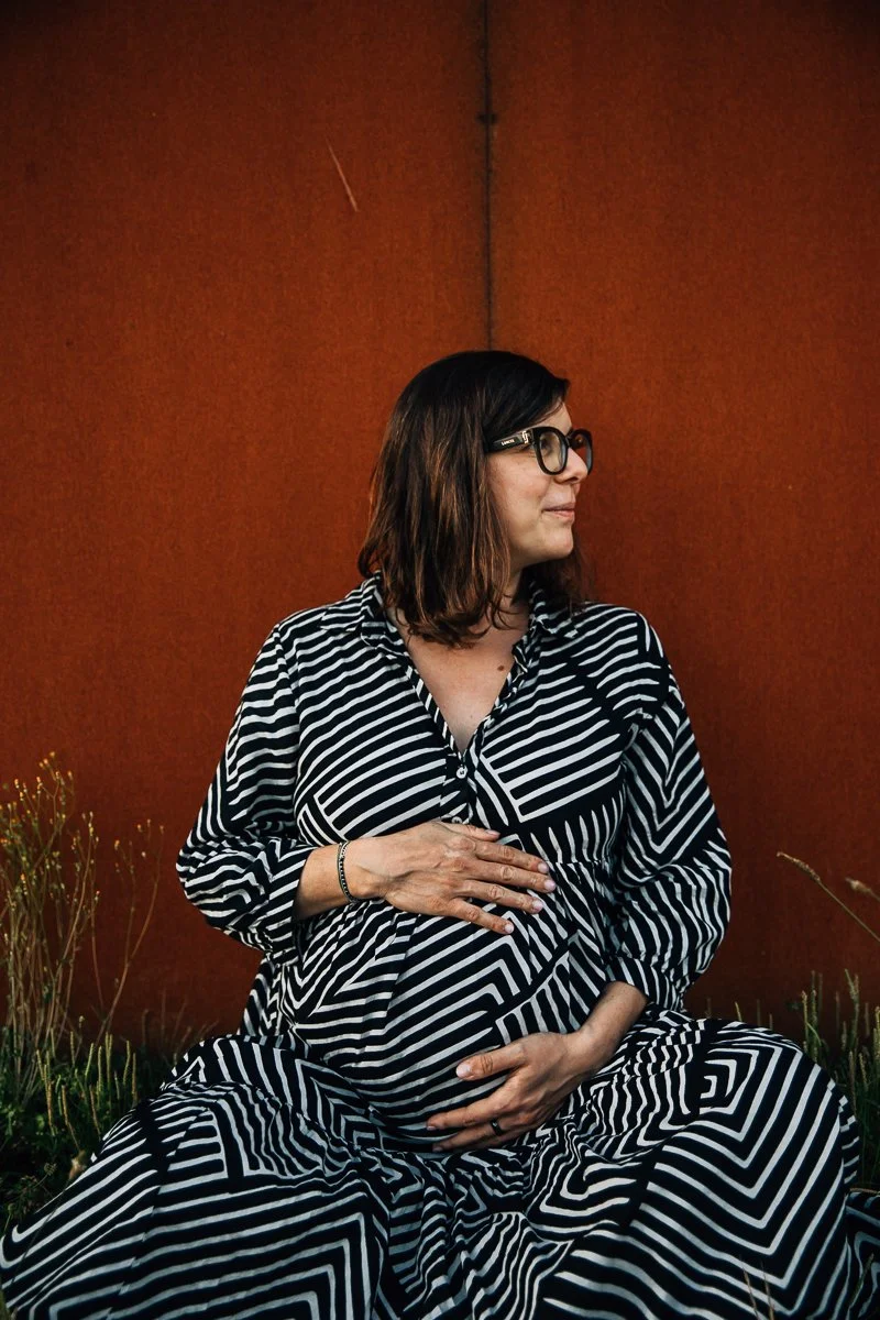 mom to be with hands on belly in a black and white dress