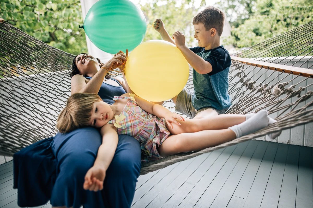 mother with 2 kids playing with balloons on hammock