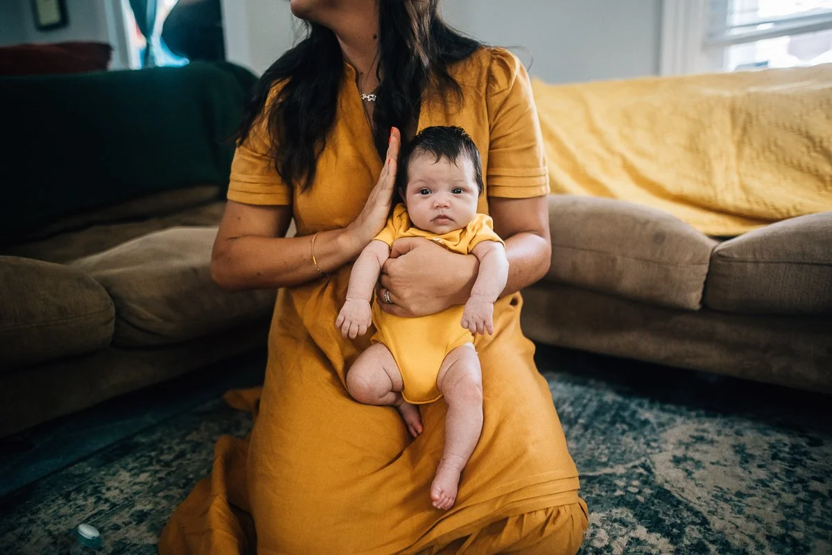 mom in yellow dress hold baby's head
