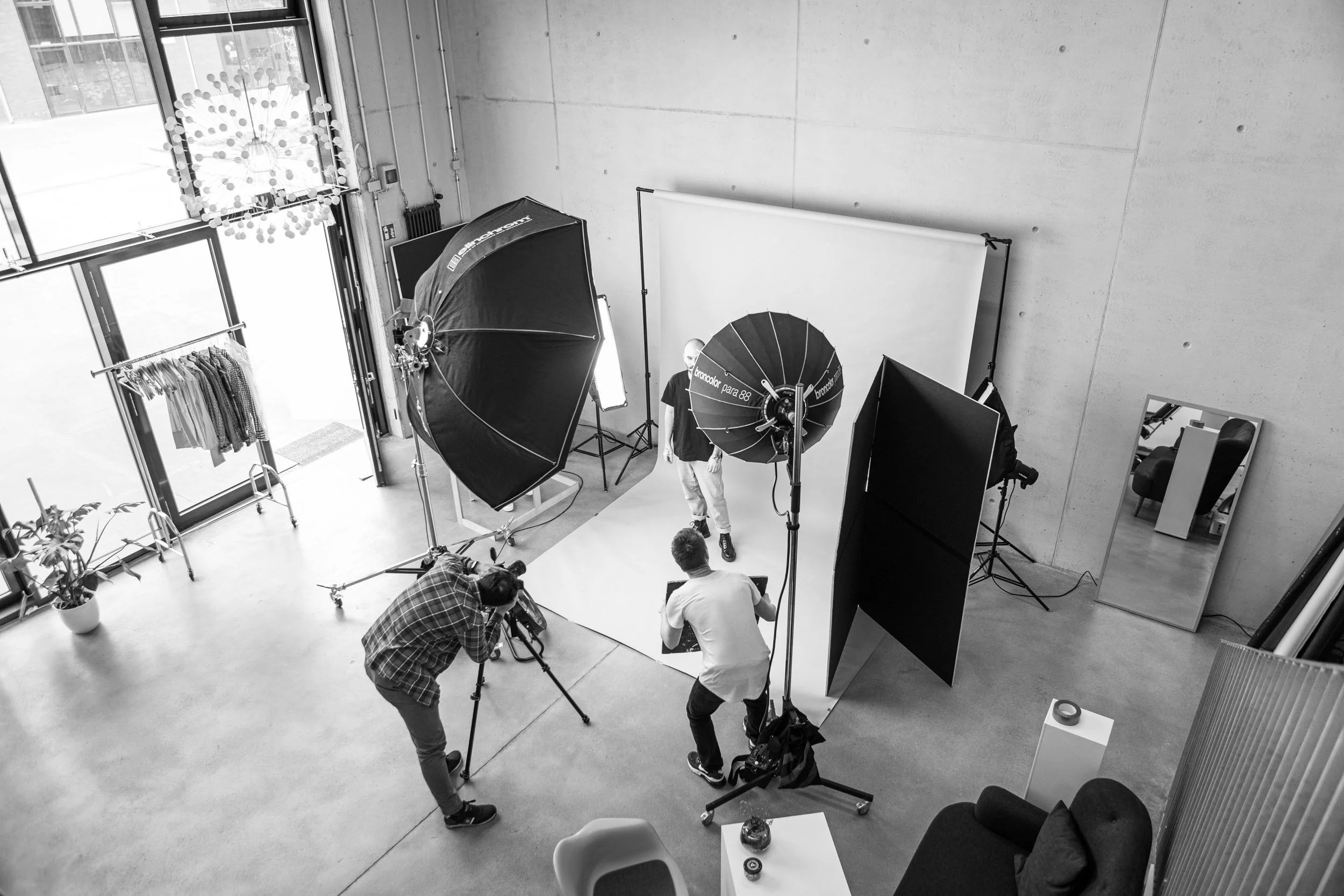Fotostudio in Clouth 104 Nippes zur Miete , Lichttechnik und Model mit Hintergrund-Stand. Das Studio ist modern mit großen Fenstern, die viel Tageslicht hereinlassen, und hat eine graue Betonwand.