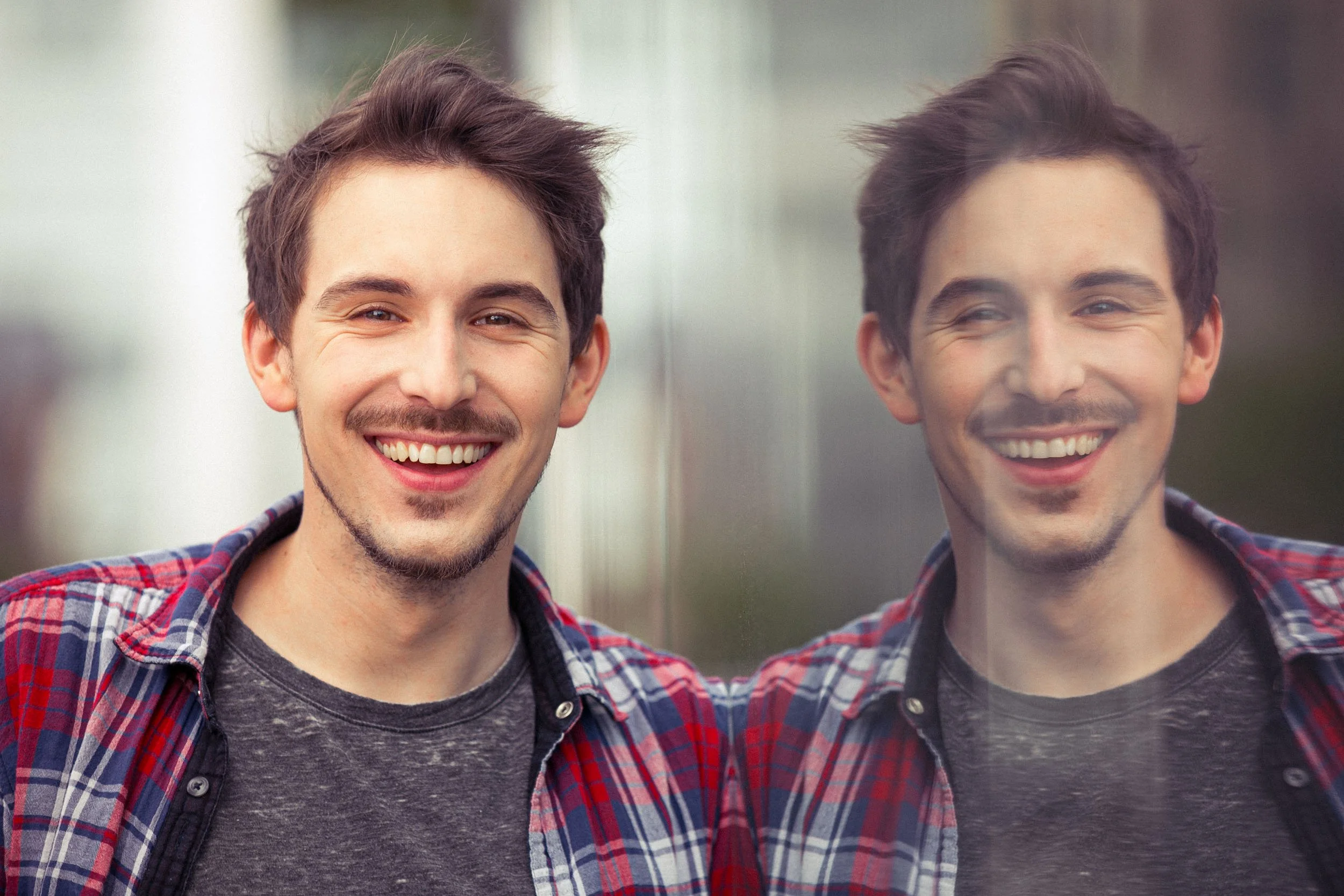 Lächelnder Mann in kariertem Hemd mit Spiegelbild.