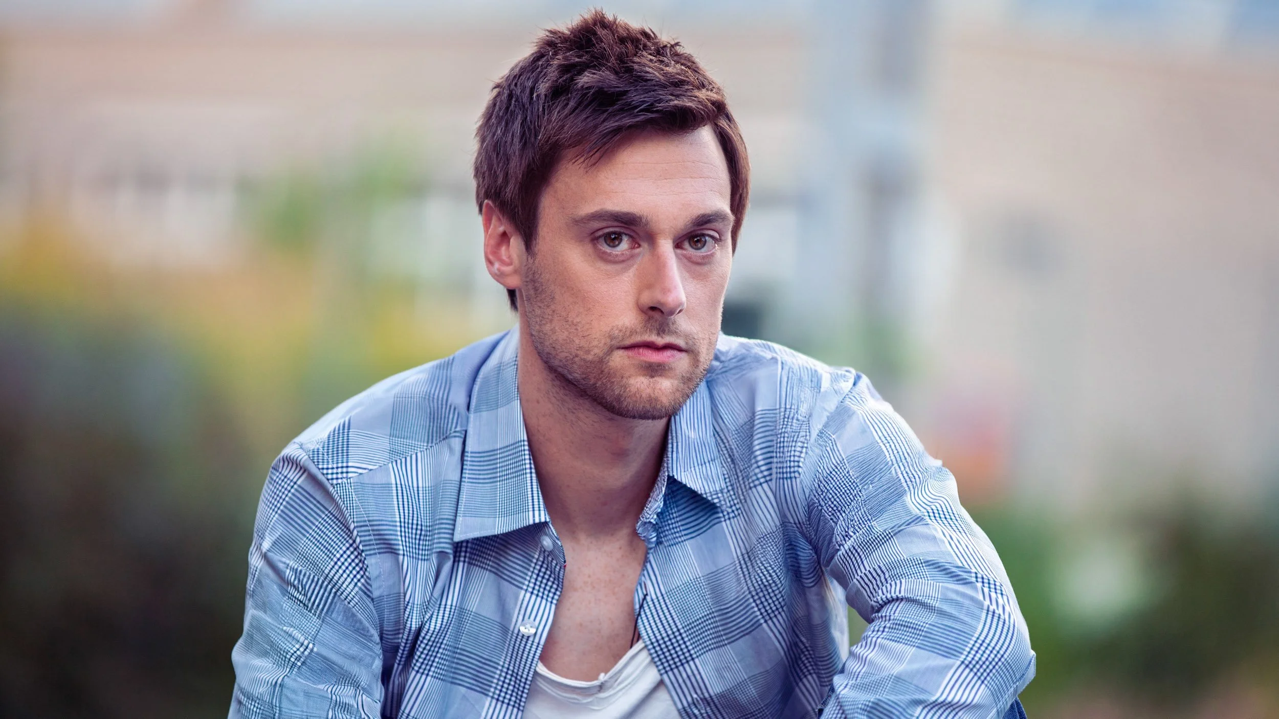 Porträt eines Mannes in kariertem Hemd draußen.