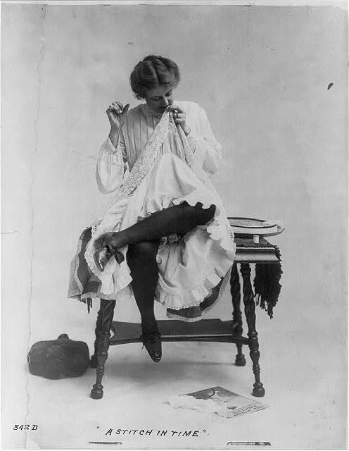 A-Stich-in-Time-Woman-seated-on-small-table-with-legs-crossed-mending-dress-which-she-is-wearing-ca.-1890-Library-of-Congress.jpg