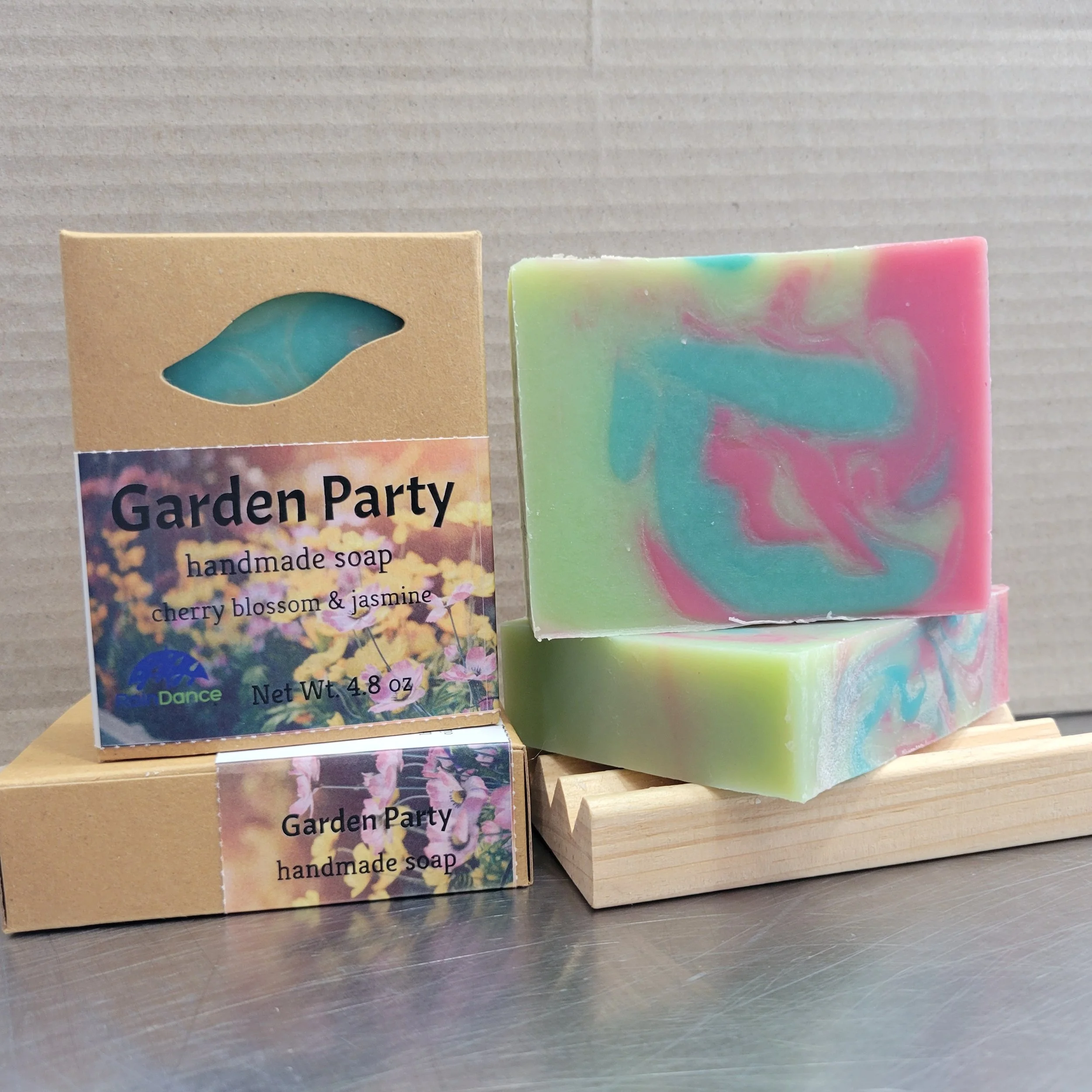 Multi-colored Garden Party soap bar by Raindance Soaps, displayed unwrapped next to its packaging box with a printed label.