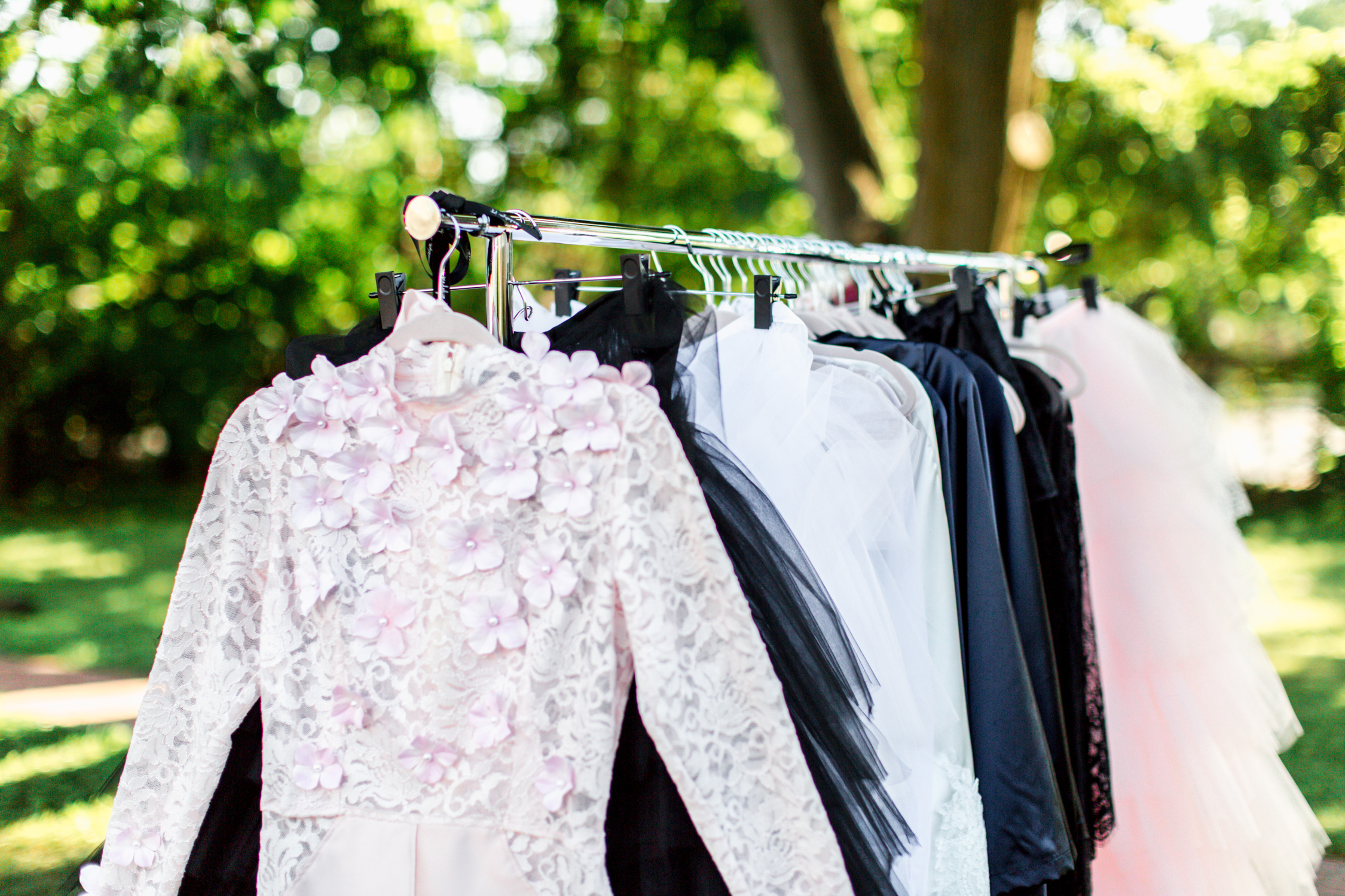 The runway looks hanging on the garment rack before the garden party fashion show. 