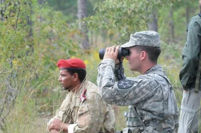 Photo Credit: Aniesa Holmes. A role player dressed as an Afghan border security officer helps a student enrolled in the Advanced Situational Awareness Training program observe a village from a distance, Oct. 4, 2013, on Lee Field at Fort Benning, Ga.