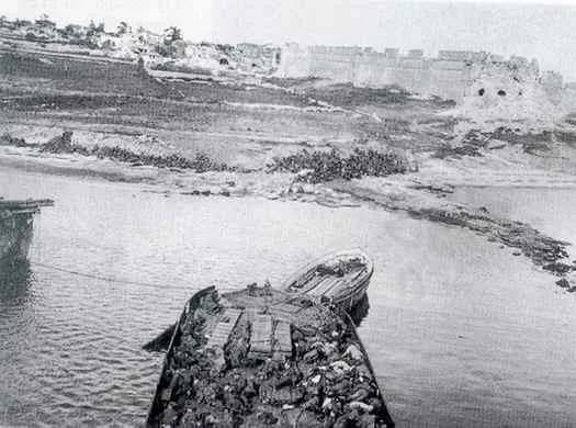A photo taken from the deck of the River Clyde looking towards the shore of V beach. There are dead and wounded men in the lighter.