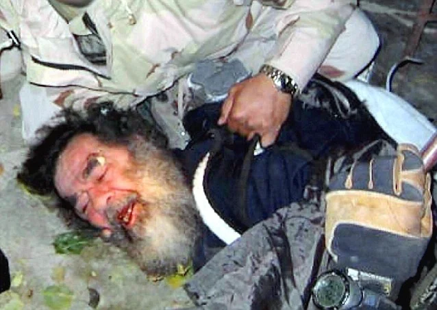 Saddam Hussein compelled to surrender by U.S. troops in December 2003.