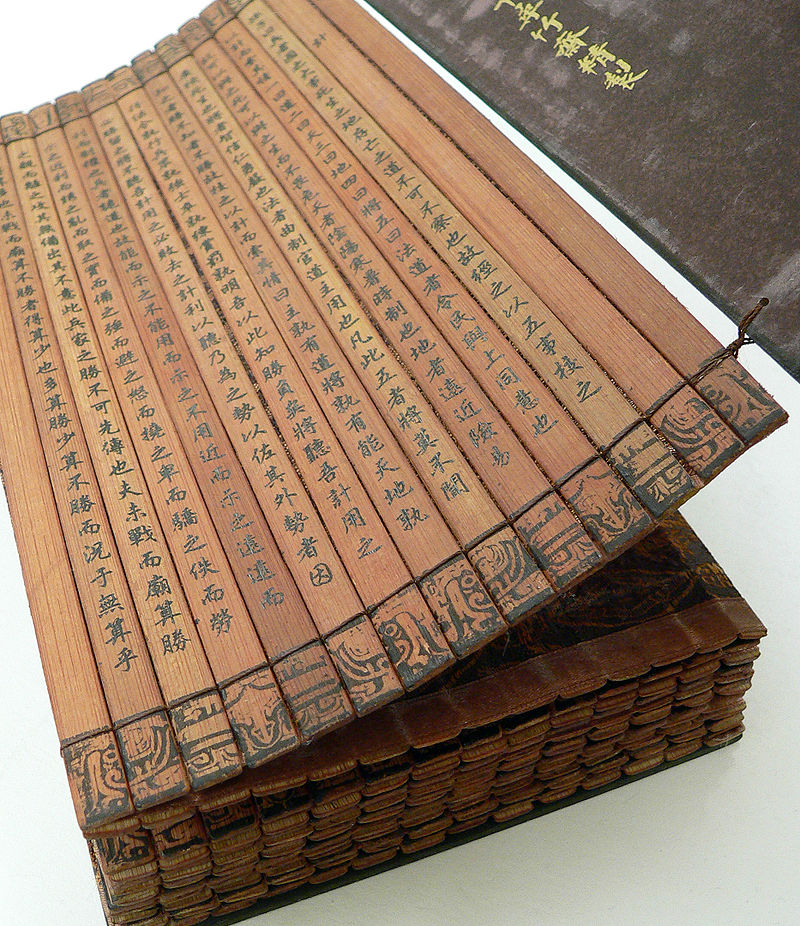 A Chinese bamboo book, open to display the binding and contents. This copy of The Art of War by Sun Tzu is part of a collection at the University of California, Riverside. (Wikimedia)