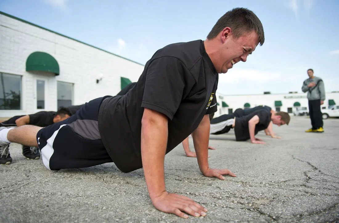 Kyle Bayard, 20, struggles to remain in position during a stationary push-up during physical exercise in the parking lot behind the Army recruiting station in Grandview, MO (Time.com)