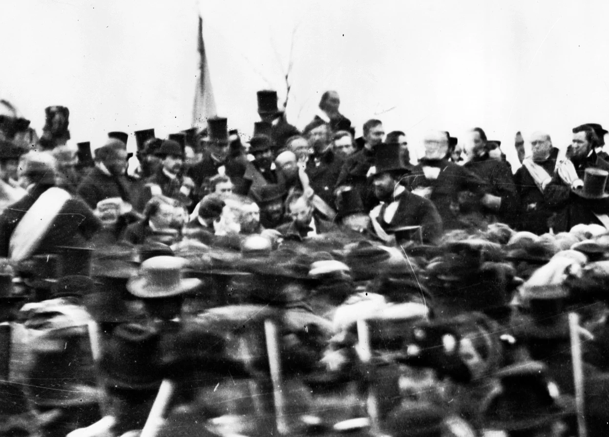 Abraham Lincoln at the dedication of the Soldiers' National Cemetery in Gettysburg, Pennsylvania. Lincoln is slightly left of center, just behind the mass of blurry people, facing the camera, head slightly down and tilted to his right. (Wikimedia)