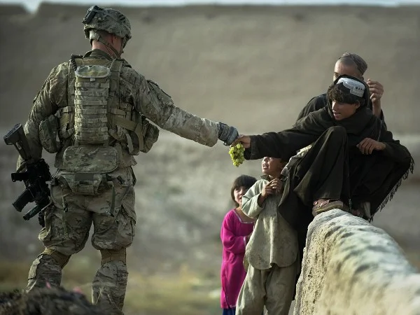 A U.S. soldier shares grapes with Afghan boys in the southern province of Kandahar. (Photo by Tony Karumba)