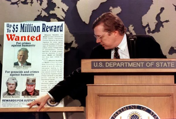 David Scheffer, U.S. ambassador-at-large for war crimes unveils a poster at the State Department in March 2000. The poster includes the images of Yugoslav President Slobodan Milosevic, Radova n Karadžić , and Ratko Mladic. (Rachel Griffith | UPI)