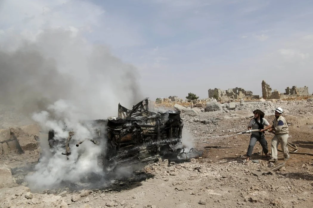 Workers dousing a burning vehicle in Idlib, Syria. Activists said the base was hit by Russian airstrikes. (Khalil Ashawi/Reuters)