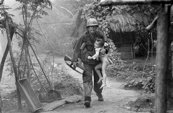 A U.S. infantryman from A Company, 1st Battalion, 16th Infantry carries a crying child from Cam Xe village after dropping a phosphorous grenade into a bunker cleared of civilians during an operation near the Michelin rubber plantation northwest of Saigon, August 22, 1966. A platoon of the 1st Infantry Division raided the village, looking for snipers that had inflicted casualties on the platoon. GIs rushed about 40 civilians out of the village before artillery bombardment ensued. (Via AP/NBCNews, Horst Faas)