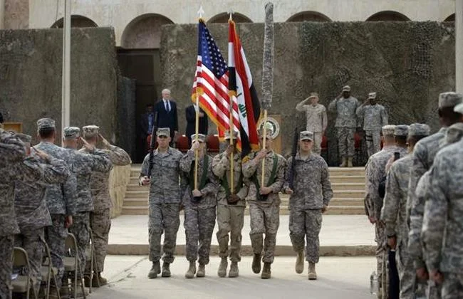 US and Iraq flag and the US Forces-Iraq colors are carried during ceremonies marking the end of US military mission in Baghdad, Iraq (Khalid Mohammed/AP)