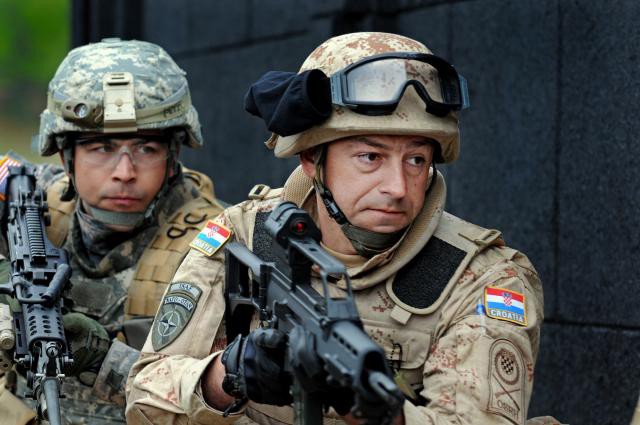 Croatian and Minnesota National Guard Soldiers prepare to clear a room during an Operational Mentoring and Liaison Team training exercise at the Joint Multinational Readiness Center