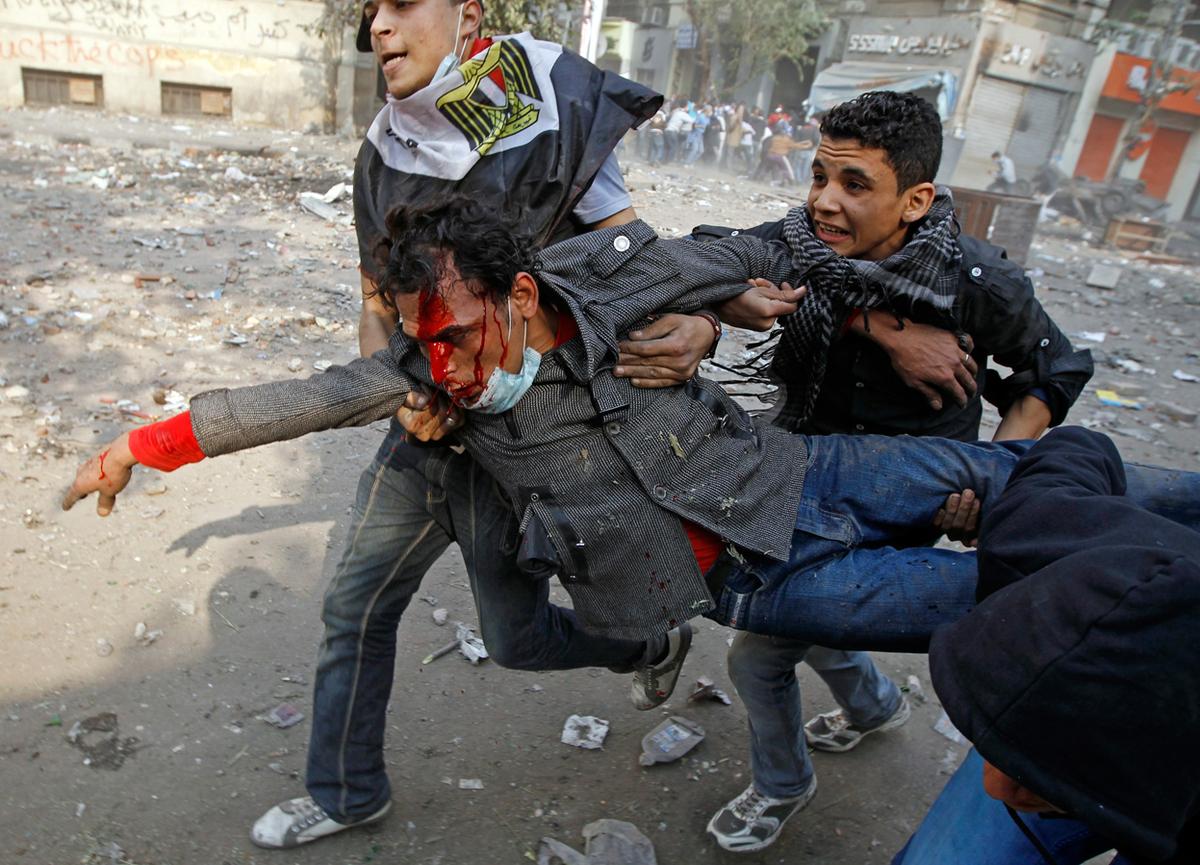 Protesters carry an injured comrade during clashes in a side street near Tahrir Square in Cairo, on November 23, 2011. (Goran Tomasevic/Reuters)
