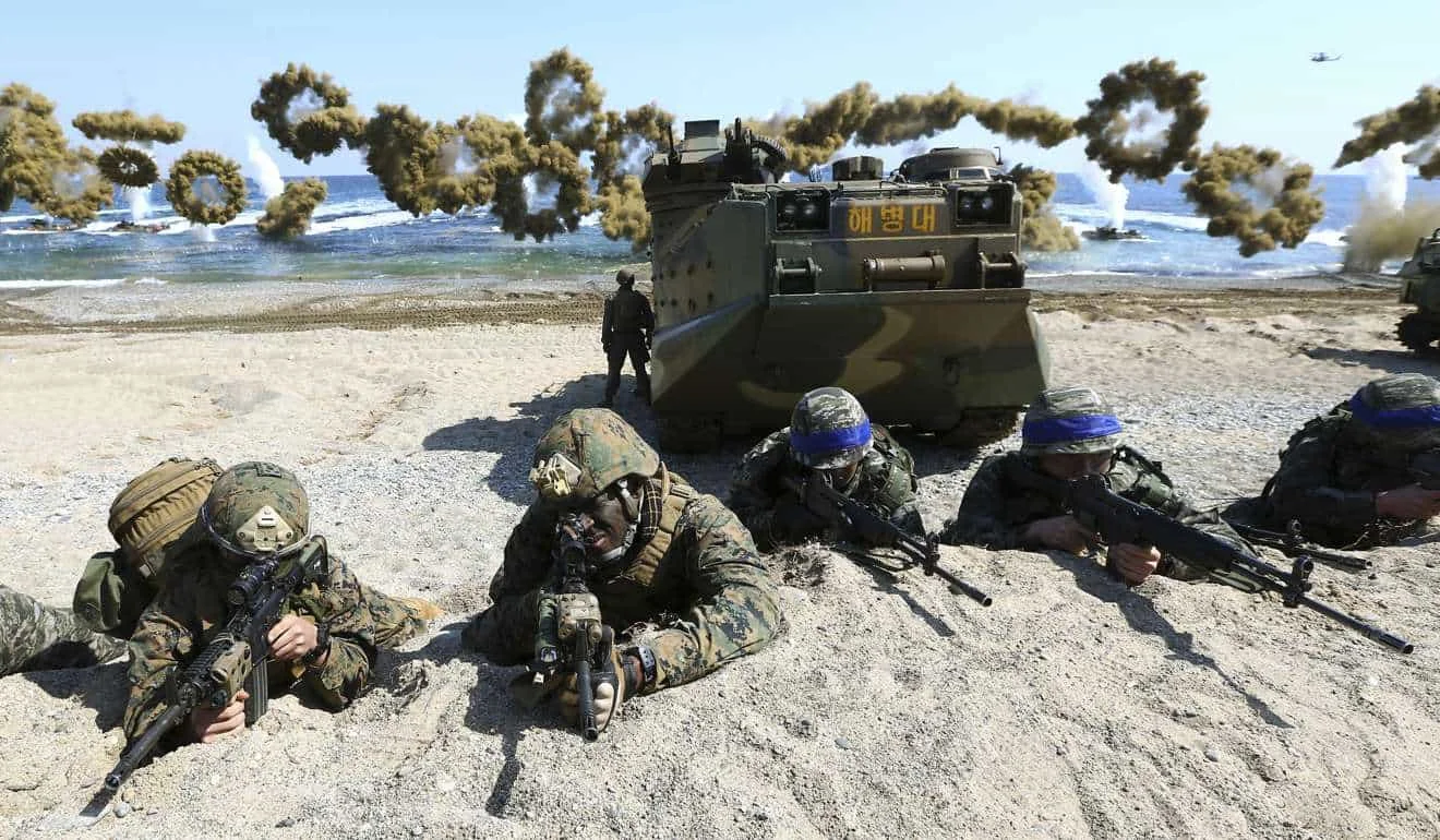 U.S. Marines, left, and South Korean Marines, wearing blue headbands on their helmets, take positions after landing on the beach during the joint military combined amphibious exercise, called Ssangyong, part of the Key Resolve and Foal Eagle military exercises, in Pohang, South Korea. (Kim Jun-bum/Yonhap/AP)