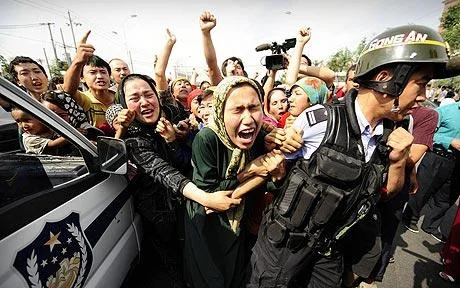 Ethnic Uygur women grab a riot policemen as they protest in 2009. (AFP)