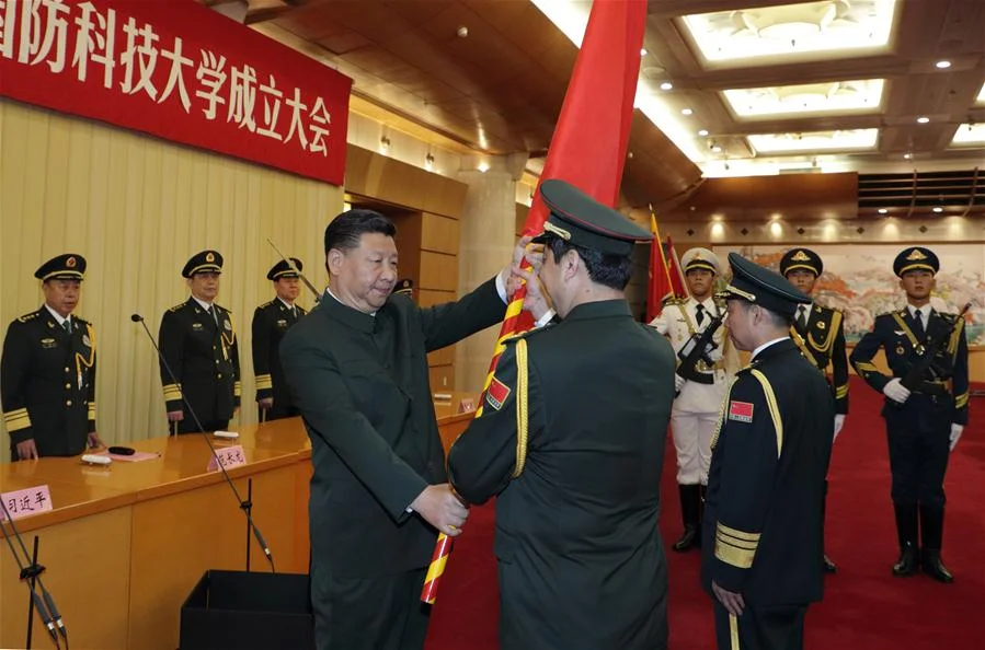 Chinese President Xi Jinping, also the chairman of the Central Military Commission, presents the heads of the People's Liberation Army Academy of Military Science with the military flag in 2017. (Li Gang/Xinhua)