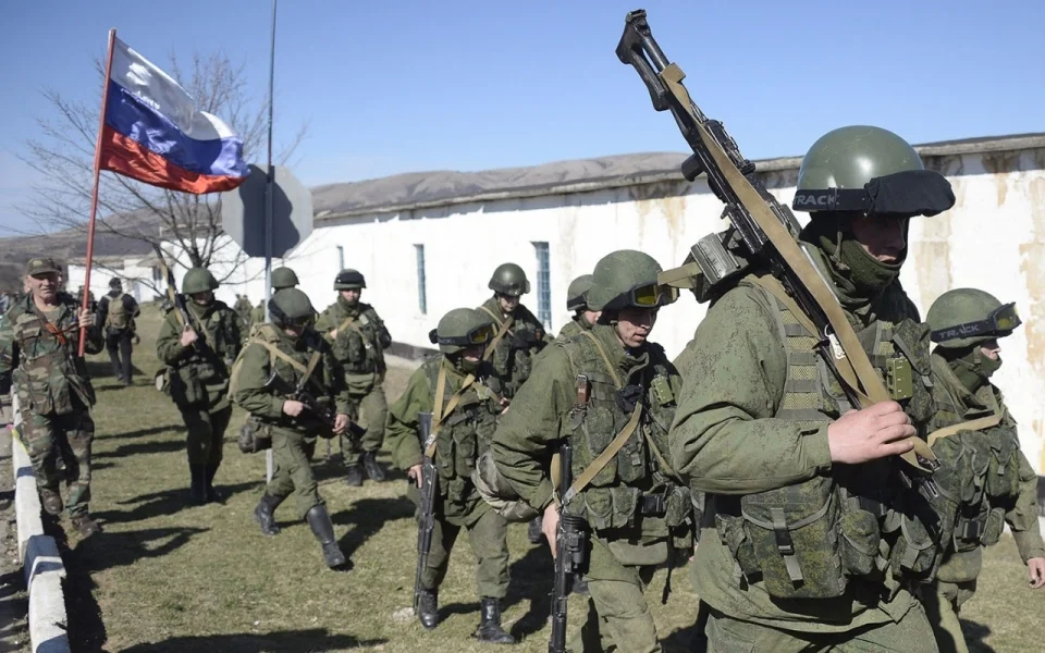 A man with a Russian flag greets armed men in military fatigues blocking access to a Ukrainian border guards base not far from the village of Perevalne near Simferopol on March 3, 2014. (Alexander Nemenov/AFP/Getty Images)