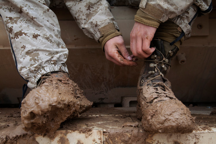 A U.S. Marine reties his boots after changing out of his wet utility uniform following an overnight rainstorm in Shurakay, Helmand province, Afghanistan, on Feb. 15, 2013. (Cpl. Alejandro Pena/USMC Photo)