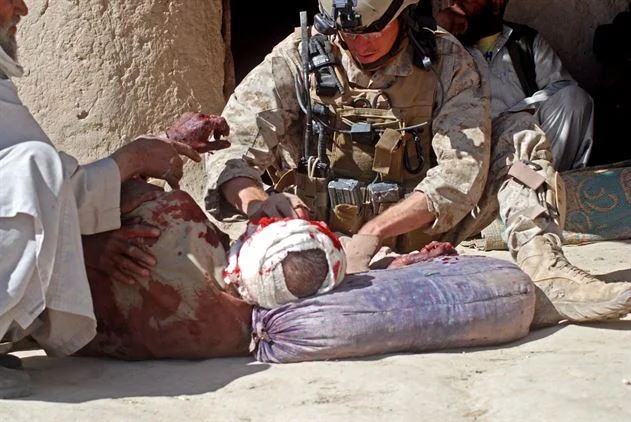 A Navy hospital corpsman treats a wounded Afghan in a Helmand Province village. (Staff Sgt. Luis P. Valdespino, Jr./Marine Corps Photo)