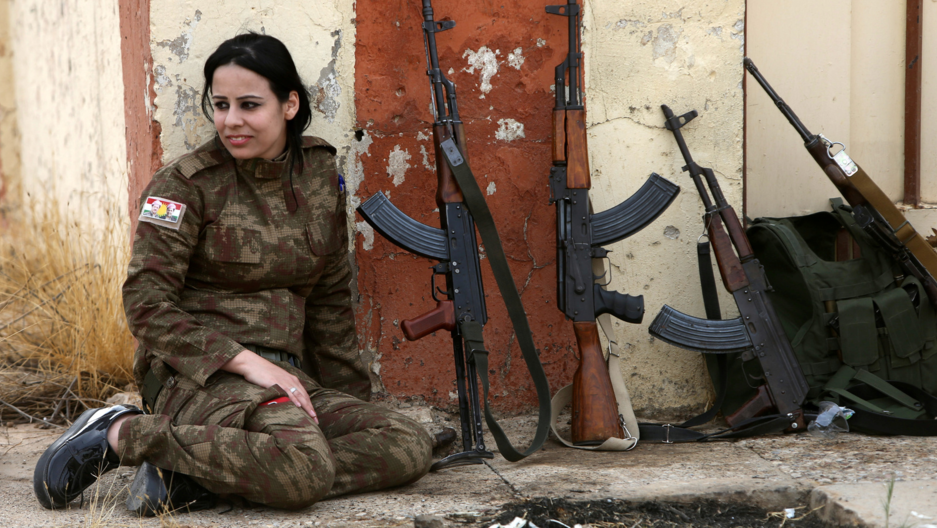 A Yazidi woman who joined the Kurdish Peshmerga forces sits next to rifles in the town of Bashiqa, after it was recaptured from the Islamic State. (Alaa al-Marjani/Reuters)